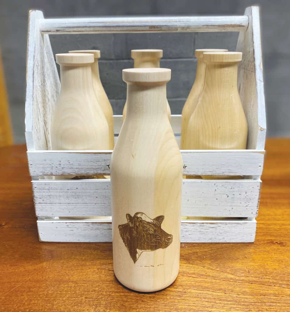 Wooden milk bottles with custom designs come from Crafted Elements.