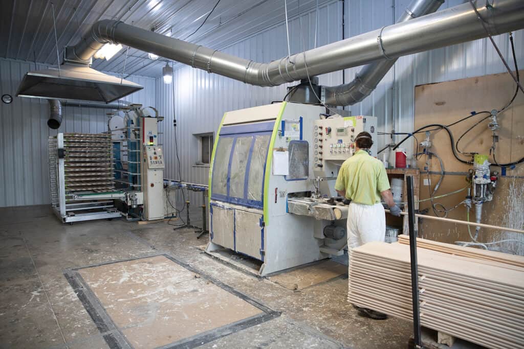 In the inline spray area at Cornerstone Moulding, an employee uses the Stanza spray machine and Makor stacker to prime and paint mouldings. Sixty percent of all product is painted.