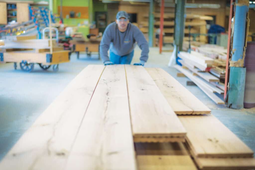 An employee moves a cart of freshly milled wide-plank livesawn White Oak flooring.