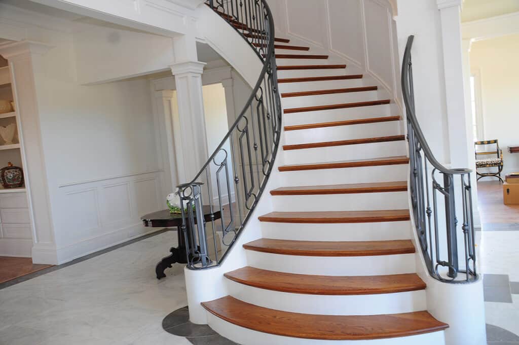 Vision Stairways and Millwork produced this double open stairway with 4-inch White Oak treads, open riser, White Oak closed stringer, with freestanding stair and landing. Included are a glass panel and square White Oak top rail.