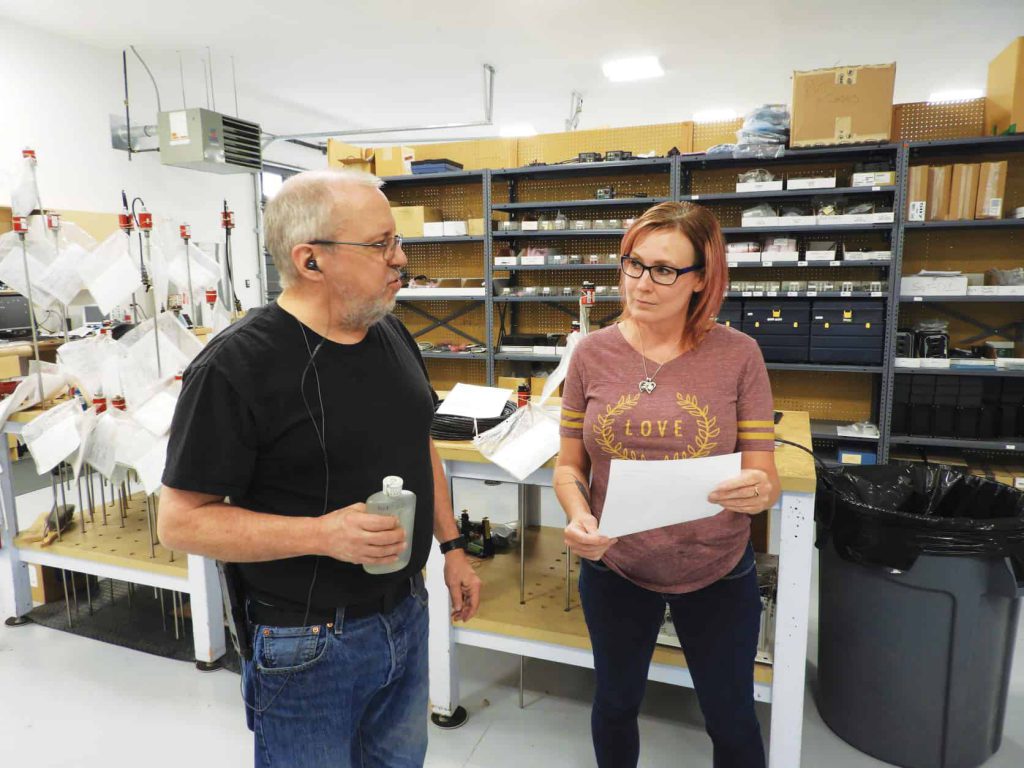 Two employees, Justina Mathews (right), production manager, and Ken Andrews, lead technician, discuss a Temposonics order and repair.